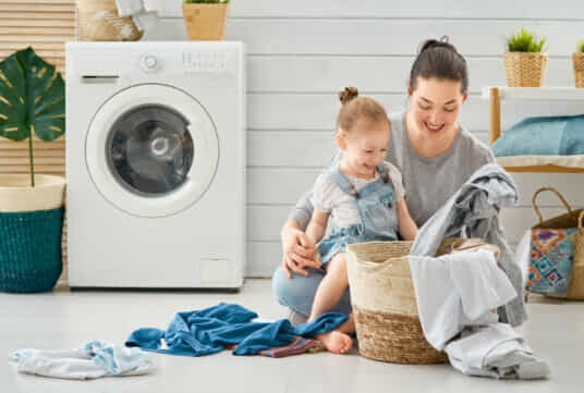 a woman sitting with her baby folding laundry