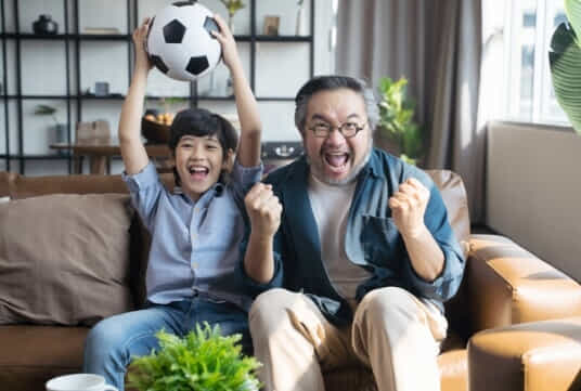 Father and son watching the world cup on their couch.