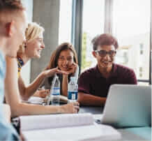 Uni studentbeans looking at a laptop screen with smile on their face.