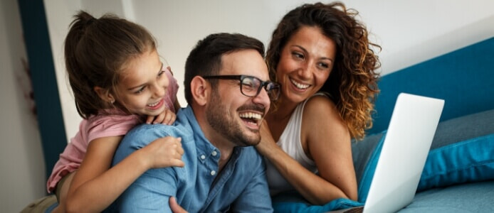 Mother, Father and Daughter smiling around a computer. 