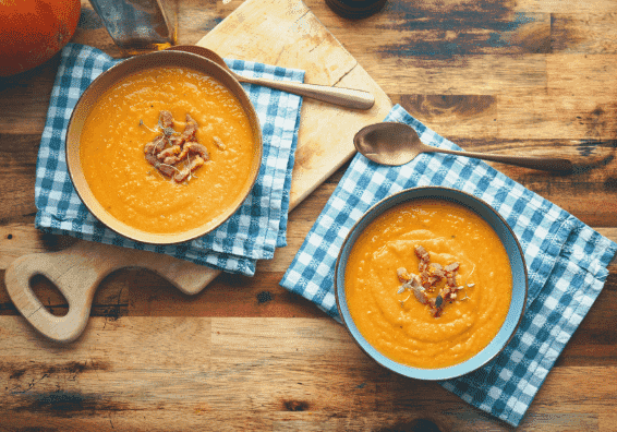 Two bowls full of soup on a wooden benchtop