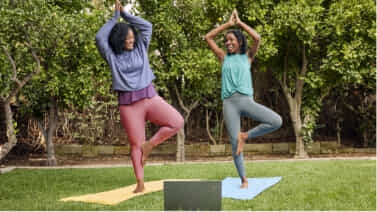 Two women practising yoga outside with their Lenovo Chromebook.