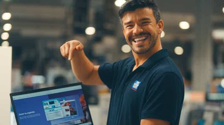 The Good Guys staff member pointing at a laptop screen with a big smile on his face.