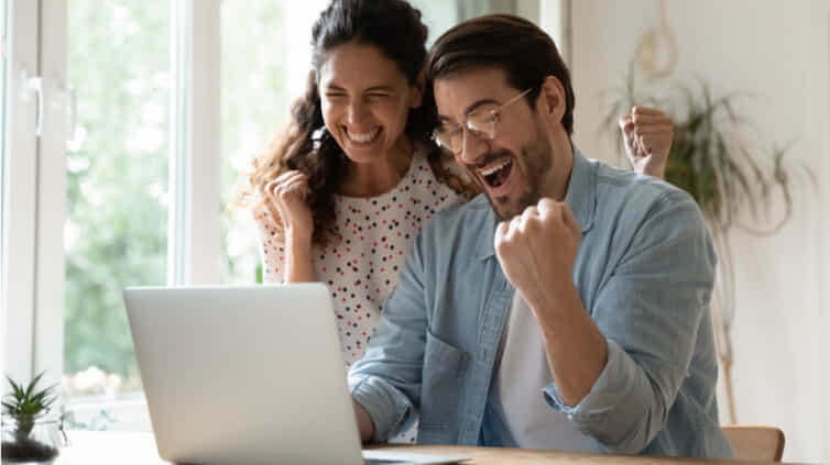 Two people looking at a laptop screen with and excited look on their faces.