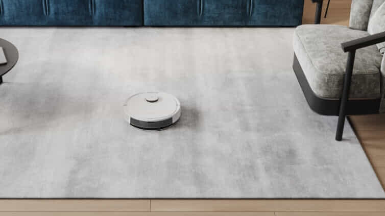 Robot vacuum cleaning a grey rug in a modern living room space.