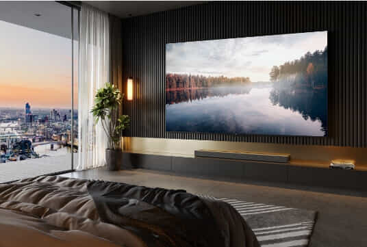 A TCL TV is mounted on the wall of a bedroom overlooking a cityscape.