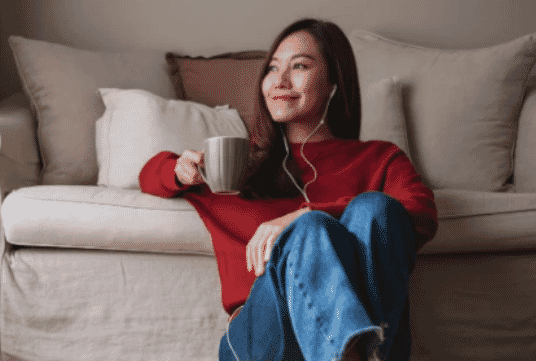 A lady relaxing with a cup of coffee and her headphones in