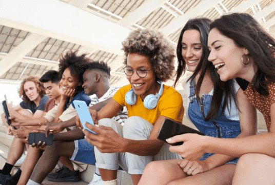 A group of teenagers sitting together looking at things on their phones