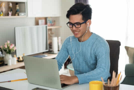 Male working on his laptop with headphones in. 