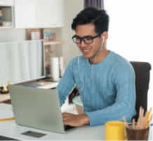 Uni student sitting at a desk working on their laptop. 