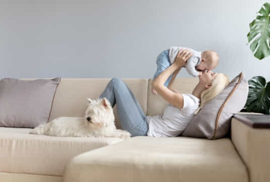 Woman with new baby and dog on couch