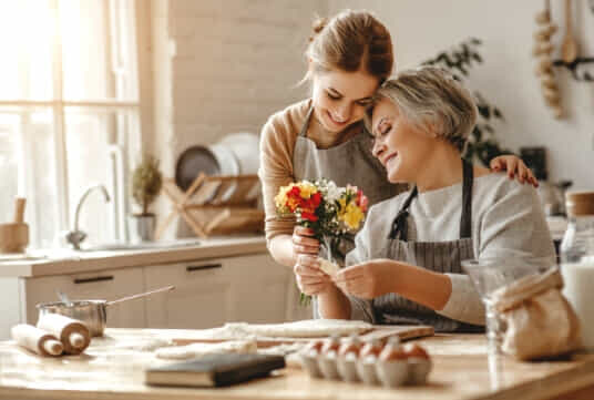 Daughter gives Mother flowers in the kitchen this Mother's Day.