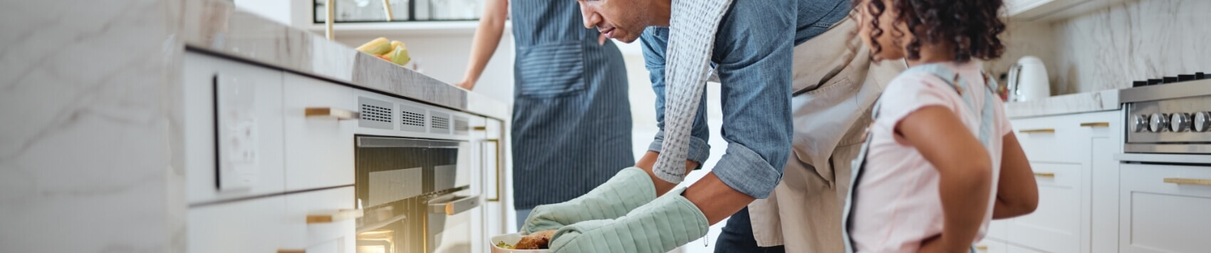 Father using an oven to cook a roast for his daughter and wide.