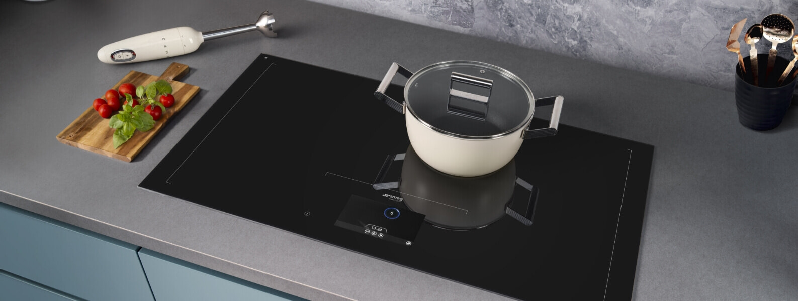 A Smeg induction cooktop in a grey kitchen with a white pot on top of it
