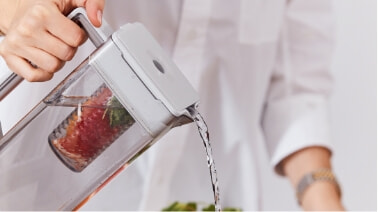 A woman pours infused water from the Autofill Water jug