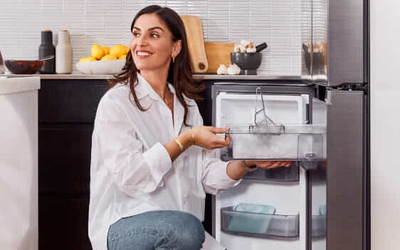 A woman pulls out the ice tray on a Samsung French door fridge.