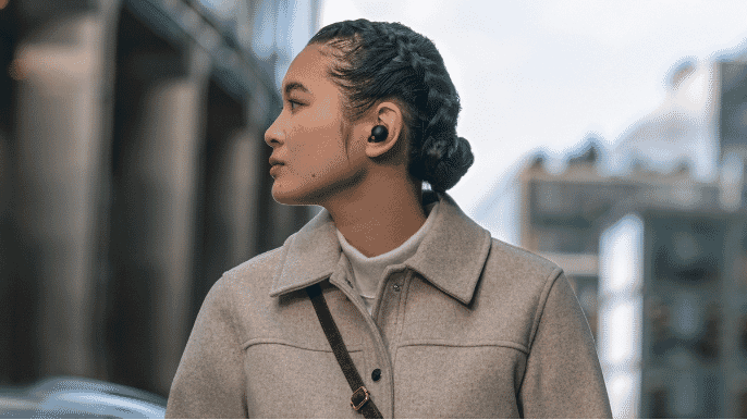 a woman walking down the street wearing her Sony WF-1000XM5 Wireless Noise Cancelling Earbuds