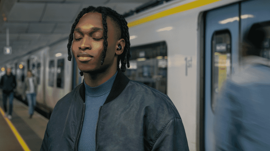 Man standing near a train listening to music with his Sony’s WF-1000XM5 Wireless Noise Cancelling Earbuds