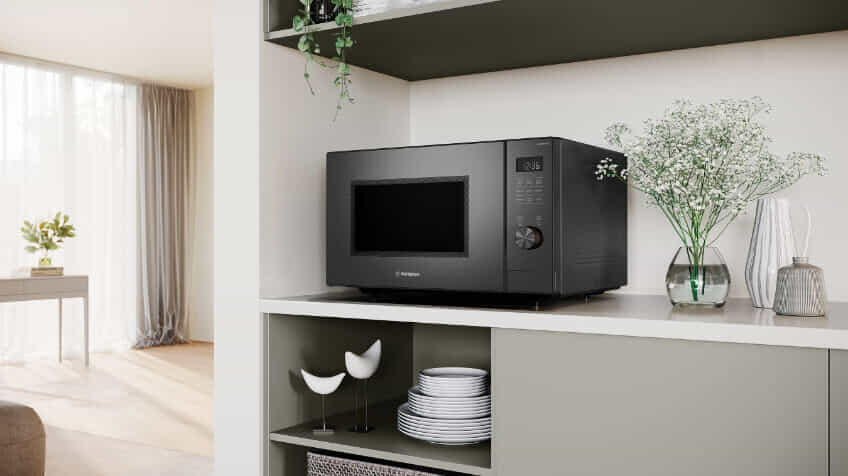 A Westinghouse microwave on a white countertop in a sage green kitchen.