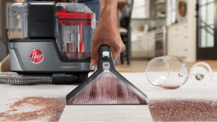 A person uses the Hoover ONEPWR CleanSlate Pet Cordless Spot Cleaner to clean a red wine stain off white carpet.