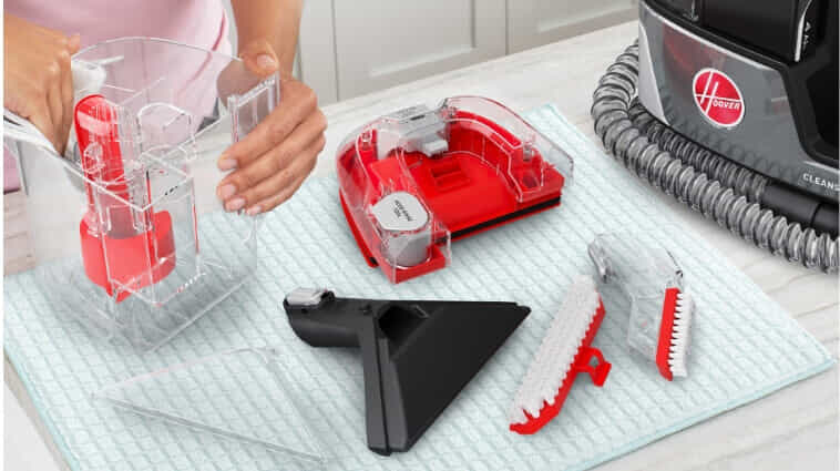 A person has taken apart the Hoover ONEPWR CleanSlate Pet Spot Cleaner and wipes it down.
