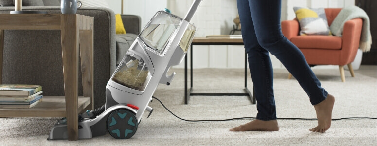 A person cleans the carpet under their console table with the Hoover SMARTWASH+ Automatic Carpet Cleaner.