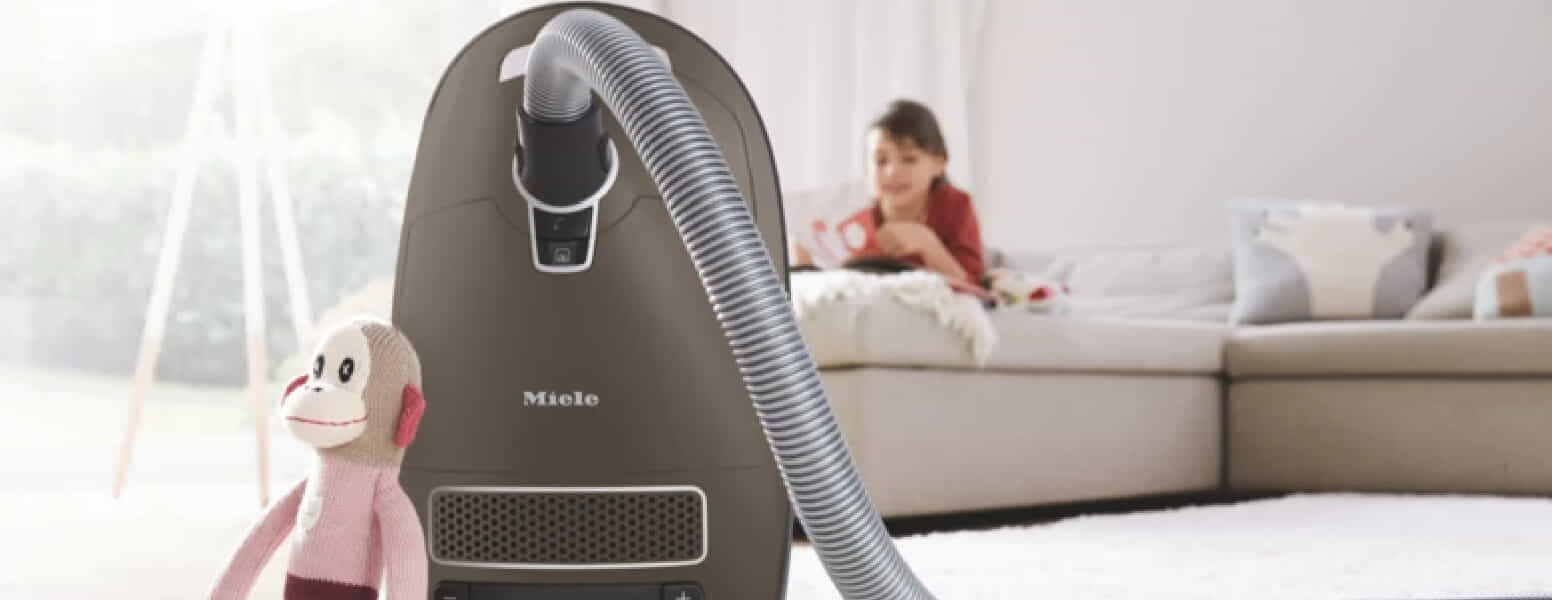 Miele barrel vacuum next to couch