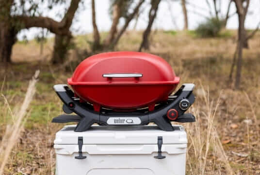 A red Weber Q+ at a camp ground in the bush