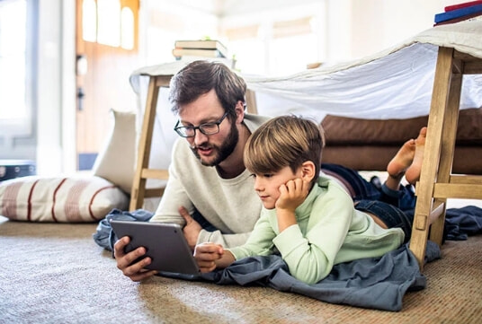 A father and his son use a tablet together.