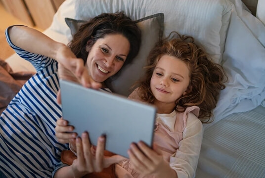 A mother and daughter use a tablet together.
