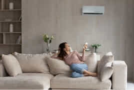 A woman relaxes on her couch as her split system cools the room.
