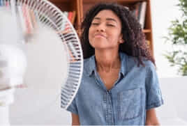 A woman cools down in front of a fan.