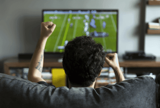 A guy watching sports on his TV