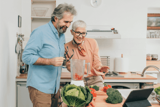 A man and woman making a smoothie in their kitchen
