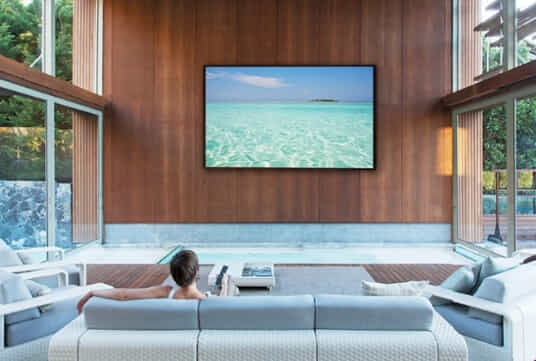 Woman watching a big TV mounted to her wall at home.