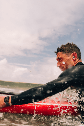 A man with a paddle board in the water wearing an Apple Watch Series 10