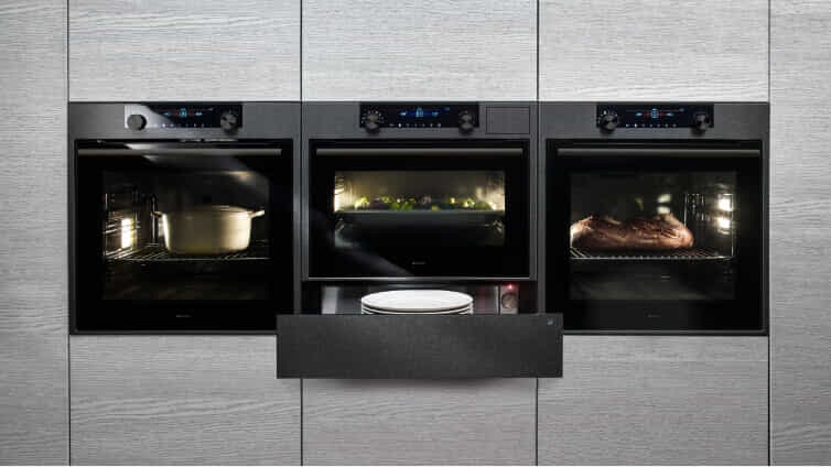 Bank of three ASKO Ovens in grey kitchen.