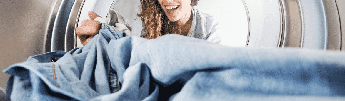 Image of a woman taking clothes out of a dryer.