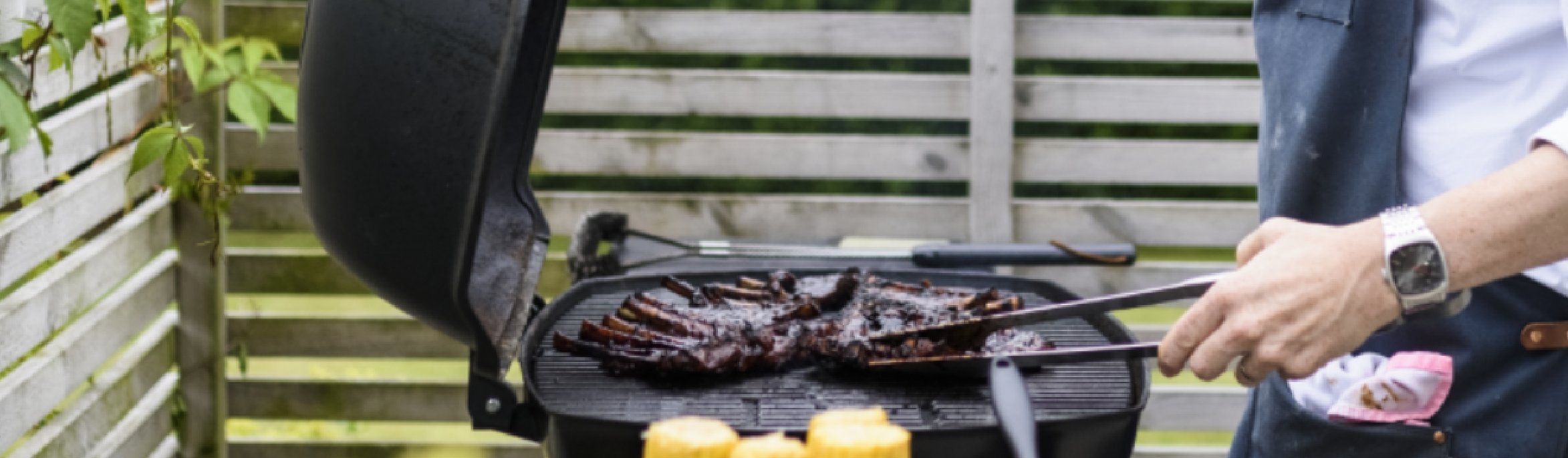 Man barbecuing ribs in a backyard.