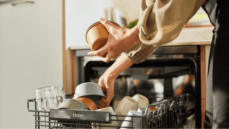 Woman stacking her Haier Dishwasher at home.