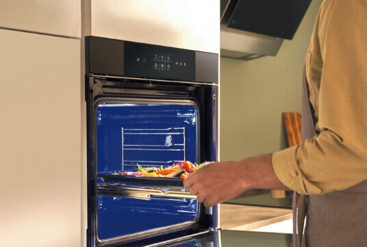 Woman putting food into her LG Oven.