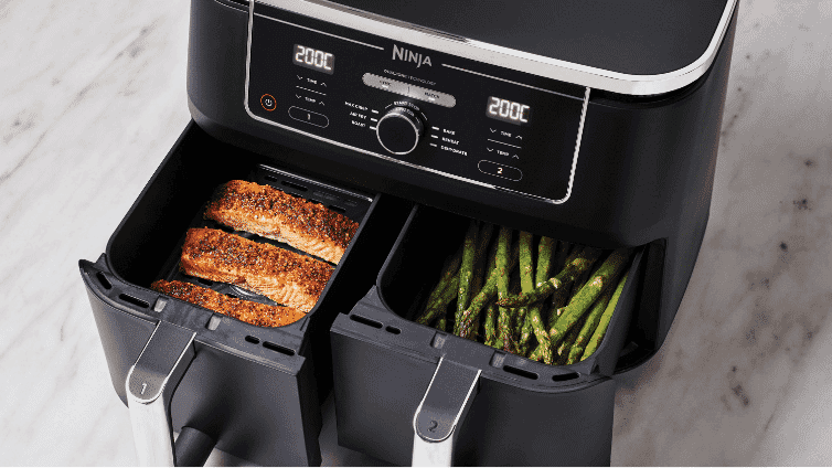 Image of a Ninja Dual Basket Air Fryer with fish cooking in one basket and asparagus in the other.