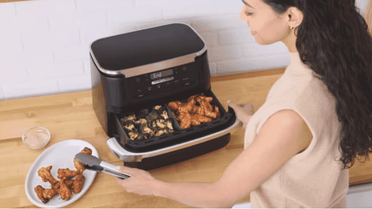 Image of a woman serving up food prepared in a Ninja Flexi Drawer Air Fryer.