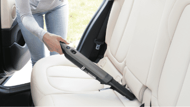 A Shark portable vacuum cleaning the inside of a car