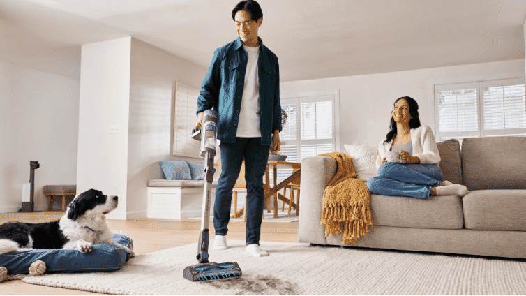 Image of a man using the Shark® PowerDetect™ Clean & Empty System to vacuum the carpet in the living room.