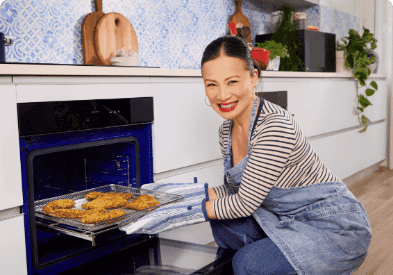 Image of Poh Ling Yeow taking her prepared meal out of an LG Steam oven.