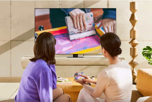 Women sitting on couch to watch Samsung lifestyle TV.