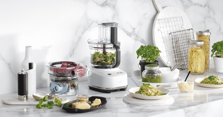 Image of a benchtop with Breville food processor on it next to dishes with prepared meals.