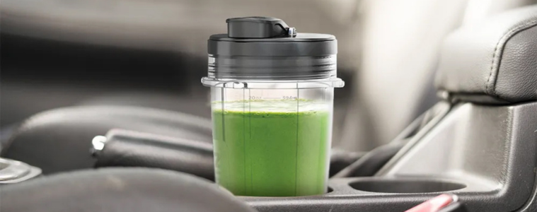 Image of a green smoothie in the Ninja Precision Blender Sip & Seal Lid in a car cup holder.