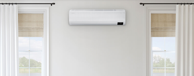 Samsung Airise WindFree Split System Air Conditioner in a living room positioned between two windows.